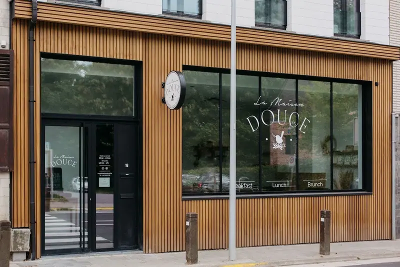 Wooden façade of La Maison Douce with a logo applied to the window