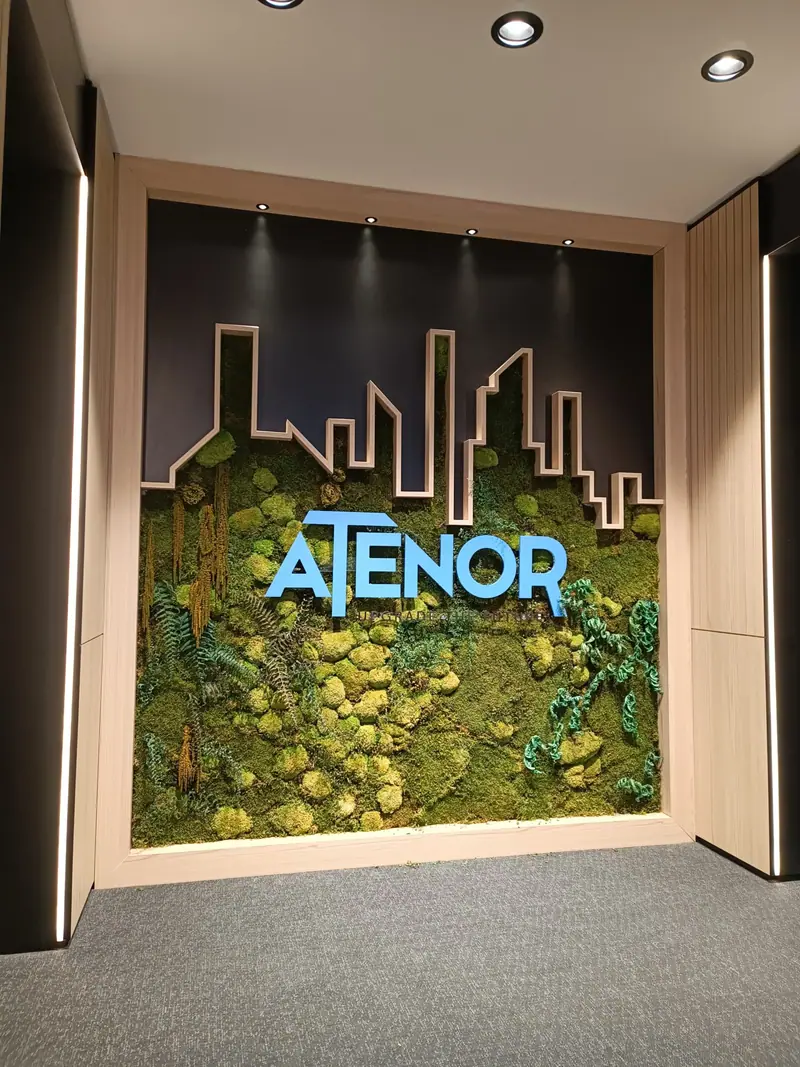 Atenor logo in large blue letters on a plant wall