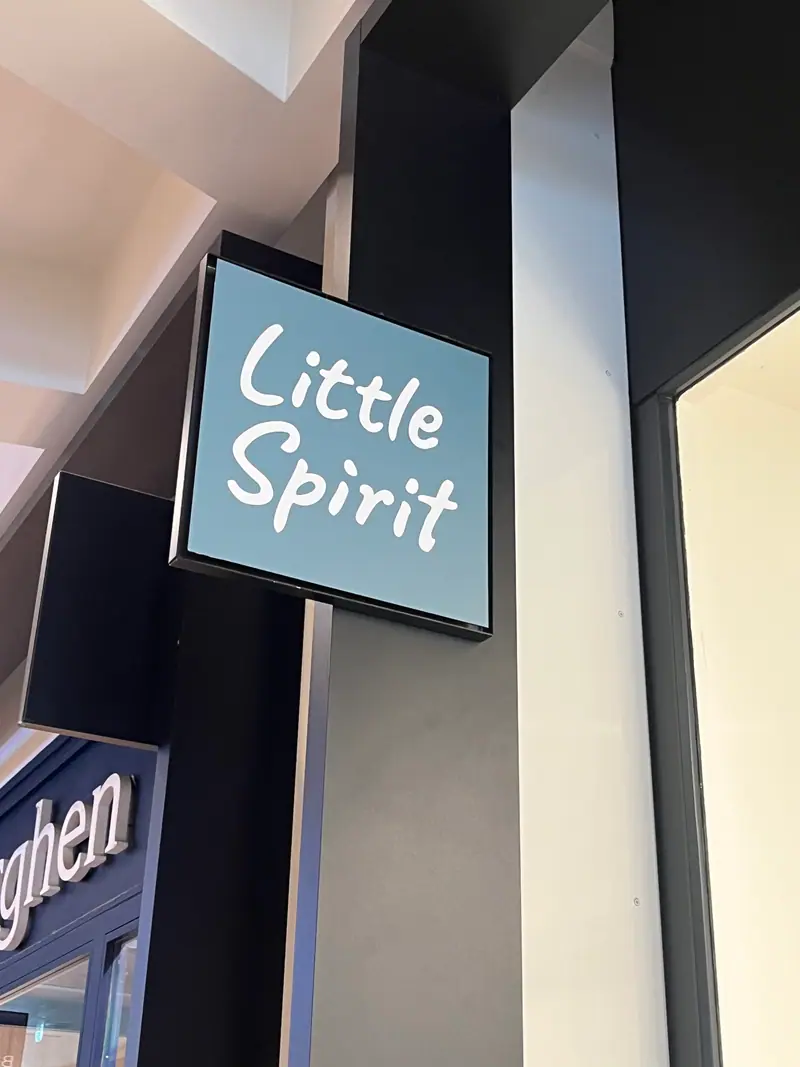 Illuminated projecting Little Spirit sign on a shop façade