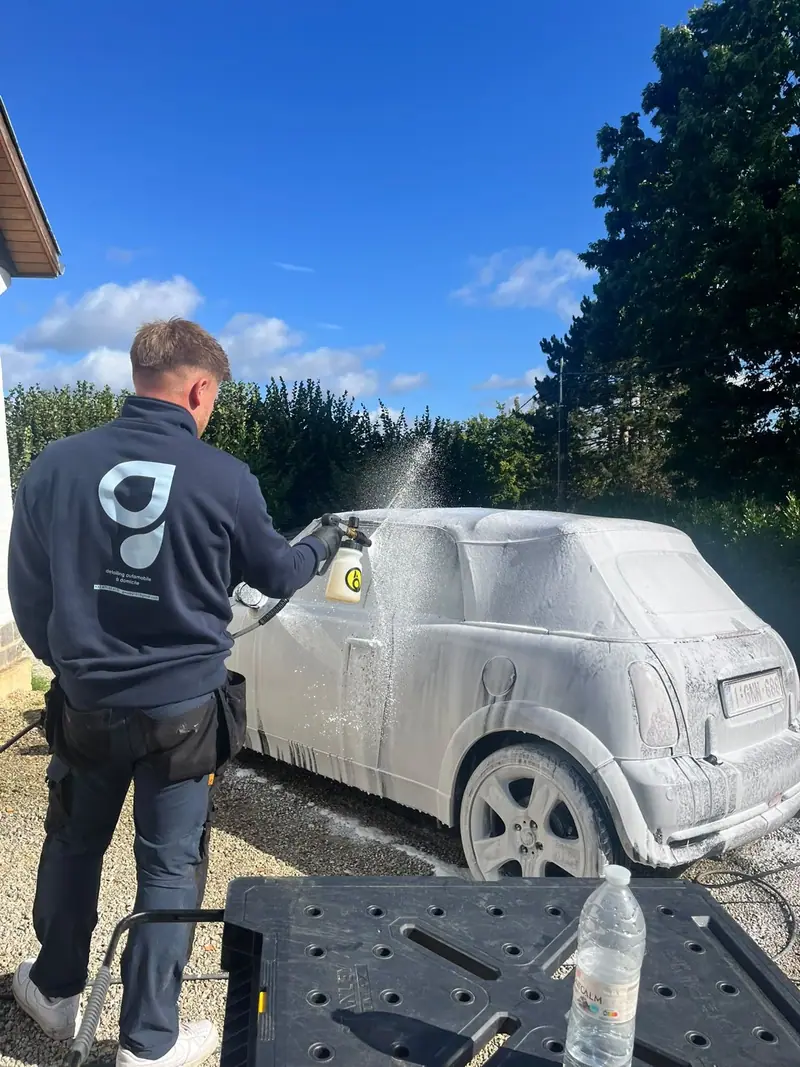 GWash employee in a custom sweatshirt cleaning a car interior