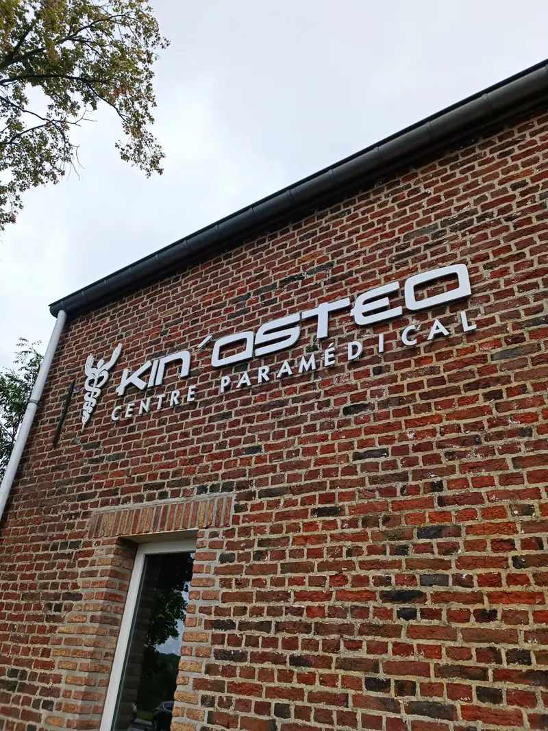 Lettered sign for Kin’Ostéo, a paramedical centre, on a brick façade