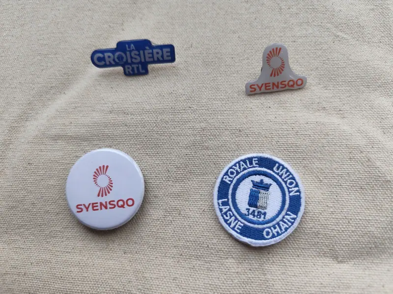 Custom pins and badges including Syensqo and La Croisière