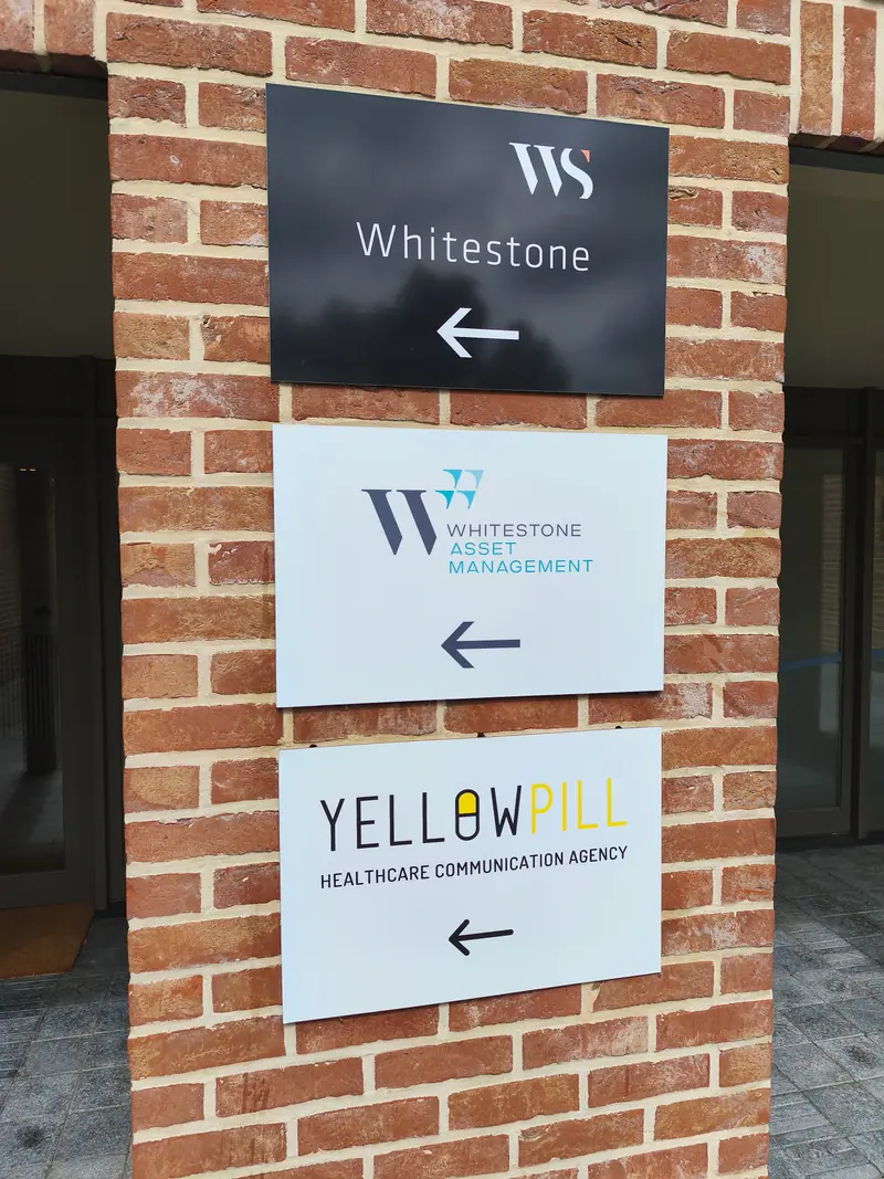 Whitestone and Yellow Pill directional panels on a brick wall