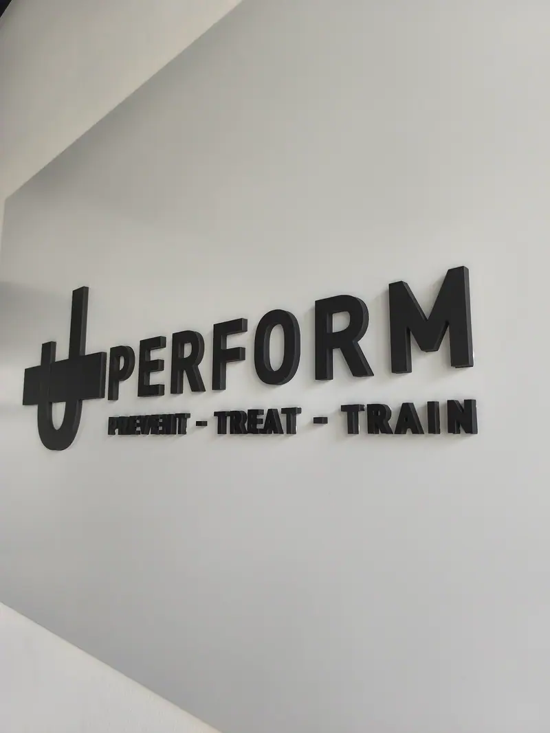 UPerform logo in black cut-out letters on a white wall