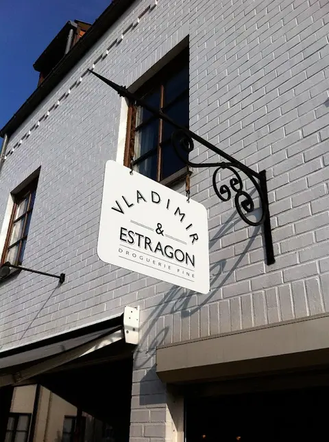 Vladimir & Estragon projecting sign, fine drugstore, on a brick façade